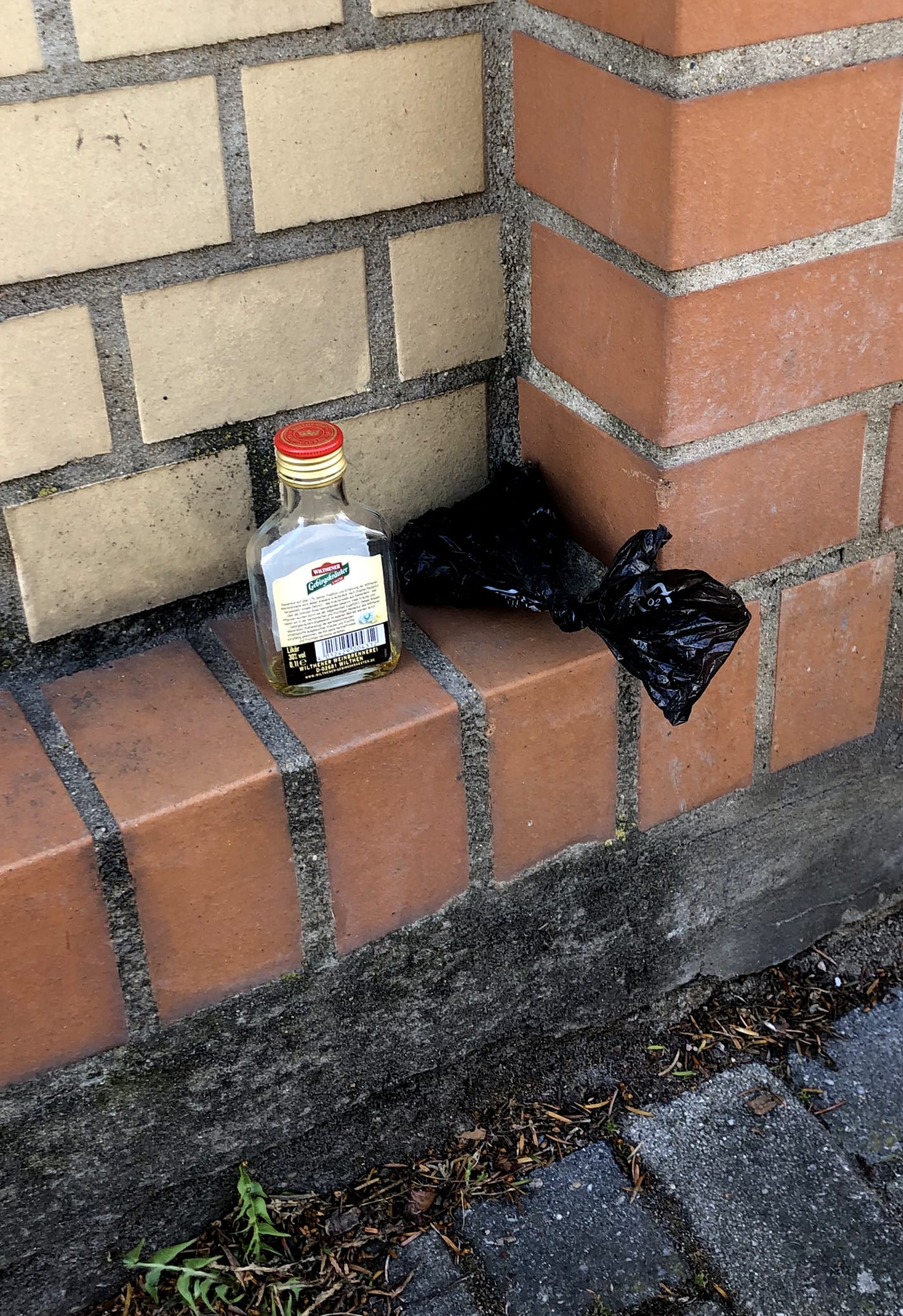 Photo: a quite odd »still life« featuring a dog fouling bag and a bottle of schnapps